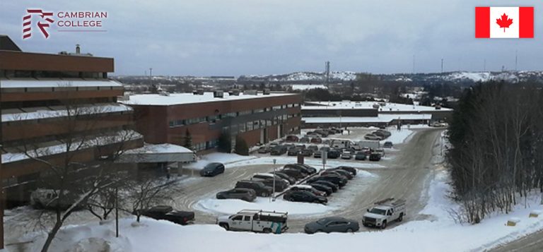 Winter view of cambrian college campus in canada, showing snow-covered parking lots and buildings with canadian flags.