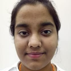 Close-up portrait of a young woman with dark hair pulled back, wearing a white-collared shirt and an orange necklace, looking directly at the camera, with a neutral expression.